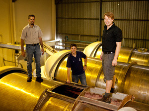 (L-r) Winemakers Willie Malan, Dirk Rust and Ben Snyman of Balance wines stand on a wine press, which extracts the juice from the grapes.
