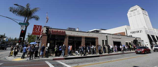 People wait in line at a Tesla Motors store in California to pre-order the "mid-priced" Model 3 electric car.