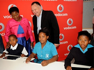 Deputy minister of human settlements Zou Kota-Fredericks and Vodacom's Alberts Breed hand over tablets to learners.