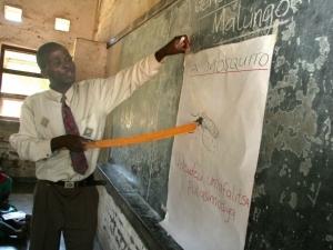 A teacher explains to students how mosquitoes infect people with malaria. CREDIT: WHO/S. Hollyman.